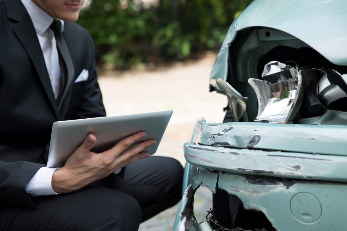 A person surveying damage done to a car