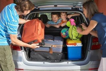 Couple Loading Luggage Into Car Trunk