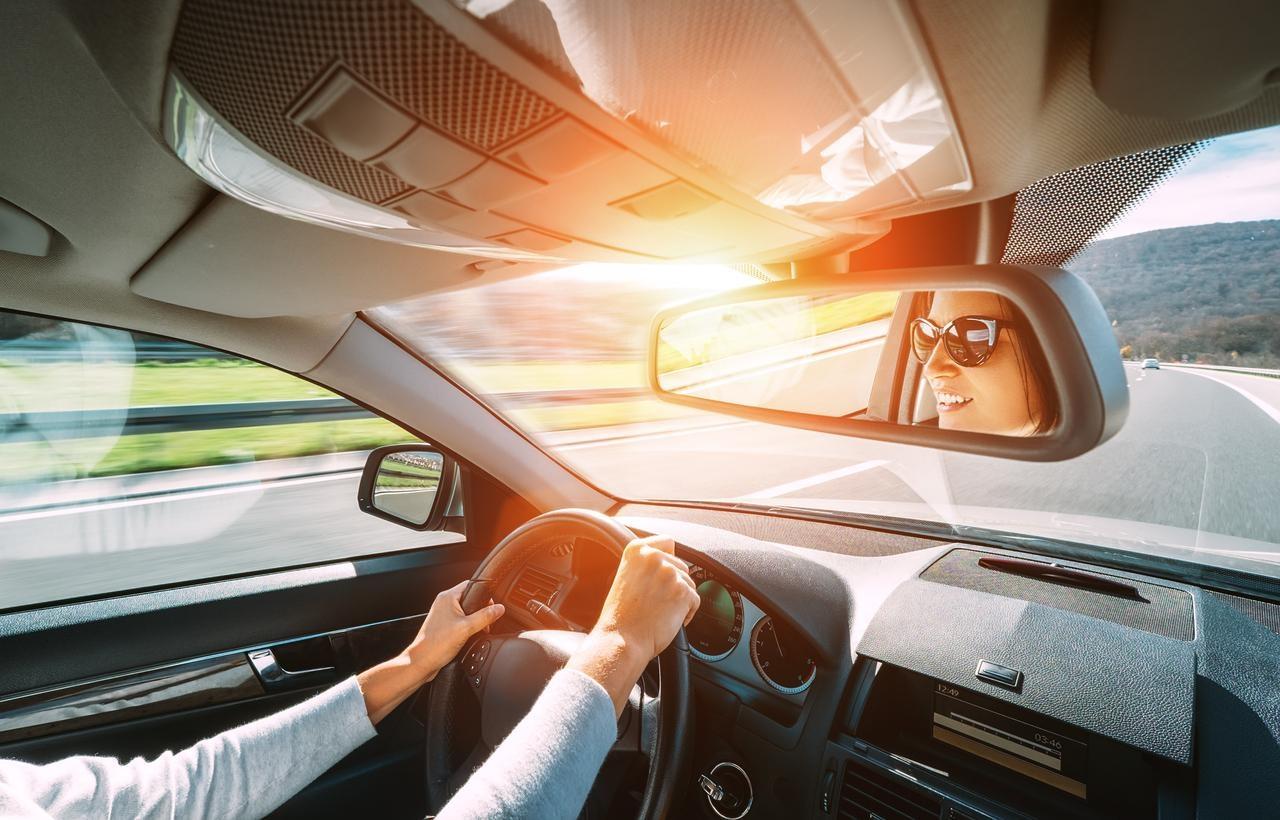 Woman driving a car reflecting in rear view mirror