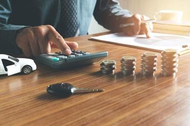 Man using a calculator to add up car hire cost