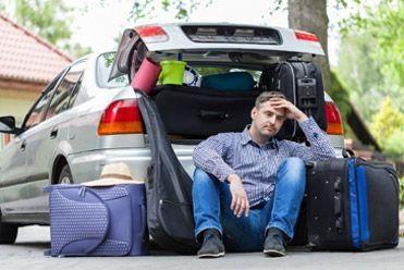 Stressed out man loading holiday suitcases into the car