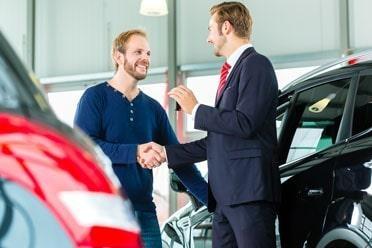 Young man and seller with auto in car hire dealership