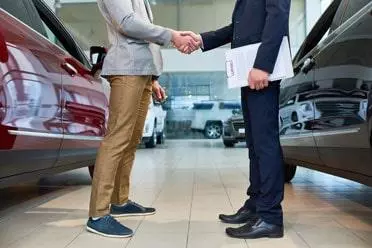 Customer and seller shaking hands at car hire dealership