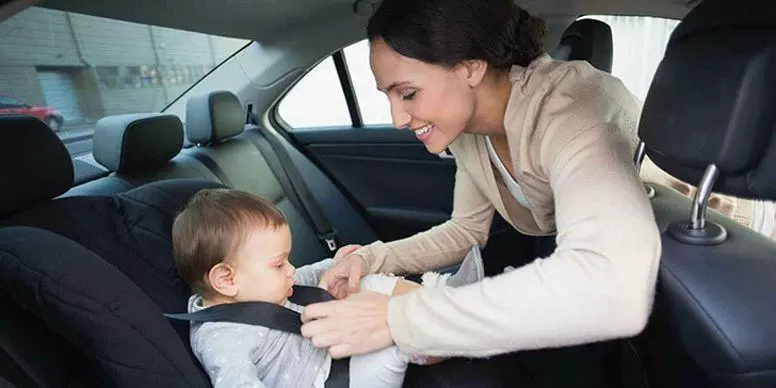 Woman putting seatbelt on child