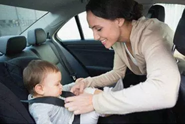 Woman putting seatbelt on child