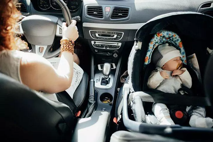 Mother driving with baby in car-seat
