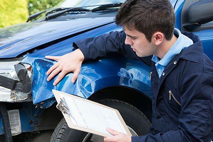 Man inspecting collision damage on car